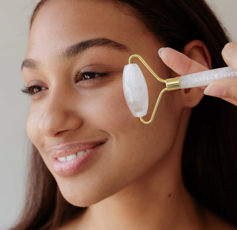Woman using a jade roller on her face with a neutral background